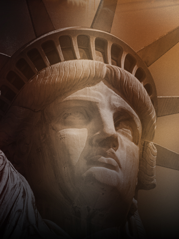 Close-up of the Statue of Liberty's face, highlighting detailed features and serene expression, against a background of the statue's crown rays.